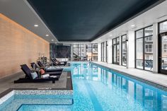 an indoor swimming pool with lounge chairs next to it