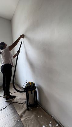 a woman is using a vacuum to clean the walls