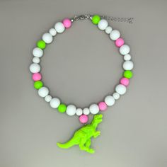 🦖 Dinosaur-Themed Statement Necklace - Unleash Your Inner Dino-Lover! These quirky dinosaur necklaces are the perfect choice for those who love bold, playful, and eco-friendly fashion. Each piece features an upcycled toy dinosaur, adding a touch of nostalgia and a unique, eye-catching charm. Ideal for anyone looking to stand out and make a statement, these necklaces bring a pop of color and personality to any outfit! ✨ Features: - Upcycled Toy Charm: Each necklace includes a toy dinosaur that's been given a second life, making it a sustainable and stylish choice. - Materials: Matte plastic beads for a soft, playful look, combined with glossy glass beads that add a hint of shine and contrast. - Stainless Steel Findings: Durable, tarnish-resistant hardware ensures your necklace stays lookin Dinosaur Necklaces, Neon Dinosaur, Kawaii Kidcore, Dinosaur Outfit, Dinosaur Necklace, Rave Party, Eco Friendly Fashion, Plastic Beads, Jurassic Park