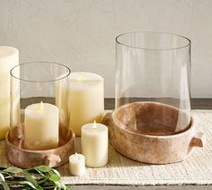 some candles are sitting on a table next to glass vases and other items that have been placed around them