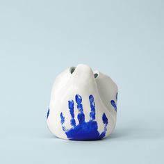 a blue and white handprinted ceramic vase on a light blue background with one hand in the middle