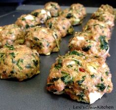 several patties with spinach and cheese are on a baking sheet, ready to be cooked