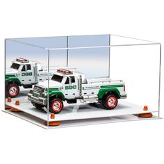 two green and white trucks are in a glass case with blue cones on the sides