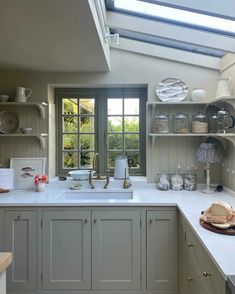 a kitchen filled with lots of white counter tops and cupboards under a skylight