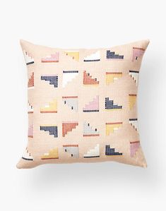 a pink pillow with colorful geometric designs on the front and back, against a white background