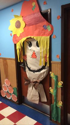 a paper mache scarecrow with a hat and flowers on it's head