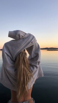 a woman with her back to the camera, looking out over water at an island