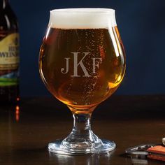 a beer glass sitting on top of a table next to a bottle and corkscrew