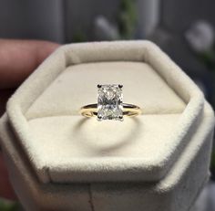 someone is holding an engagement ring with a princess - cut diamond in the middle,