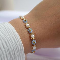 a close up of a person wearing a bracelet with beads and pearls on their arm