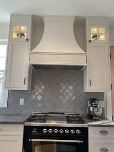 a stove top oven sitting inside of a kitchen next to white cupboards and drawers