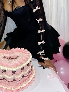 a woman sitting in front of a pink cake