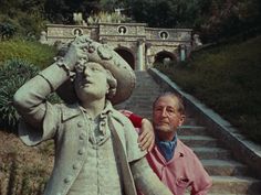 a man standing next to a statue in front of a stone stairway with steps leading up to it