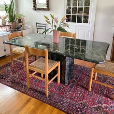 a dining room table with chairs and a rug on the floor