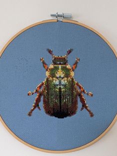 a close up of a cross stitch bug on a wall