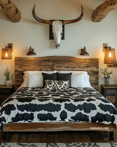 a bed with black and white bedspread sitting under two mounted steer head lights