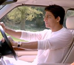 a man sitting in the driver's seat of a car with his hand on the steering wheel