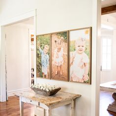 three pictures hang on the wall above a wooden table in a room with hardwood floors