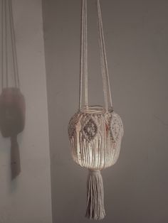 a white hanging light fixture with tassels and beads on it's sides