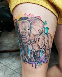 an elephant tattoo on the leg of a woman's thigh with watercolor splashs