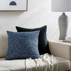 a couch with two pillows on it and a lamp in the corner next to it