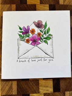 an envelope with flowers in it on top of a wooden table