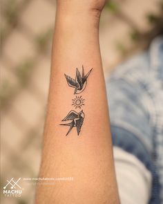 a small tattoo on the arm of a person with a bird and sun behind it