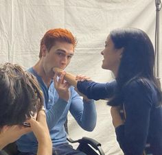 a group of people sitting around each other in front of a white backdrop with one woman brushing her teeth