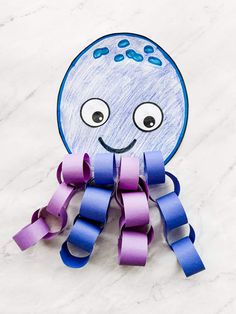 an octopus made out of toilet paper on a white surface with purple and blue streamers