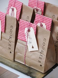 several brown bags with red and white checkered paper tags tied to them, sitting on a table