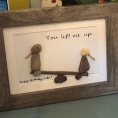 two stuffed animals sitting on top of a table next to a framed sign that says, you lift me up