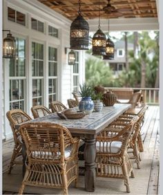 an outdoor dining area with wicker furniture and hanging lanterns above the table, along with potted plants