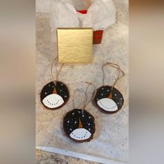 three black and white ornaments hanging on a wall next to a paper bag with gold foil