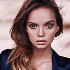 a beautiful young woman with long hair and blue eyeshadow looking at the camera