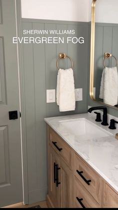 a bathroom with two towels hanging on the wall and a large mirror over the sink