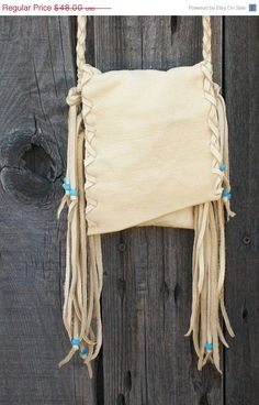 a white bag hanging on the side of a wooden fence with blue beaded handles