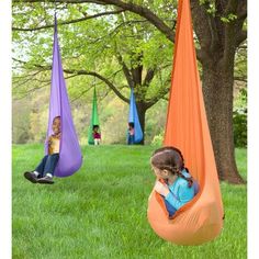 two children are sitting in hammocks on the grass