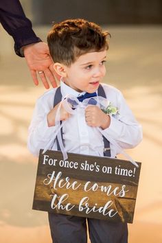 a little boy holding a sign that says for once she's on time her comes the bride