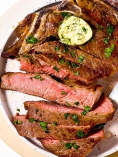 the steak has been sliced and is ready to be served on the plate with butter