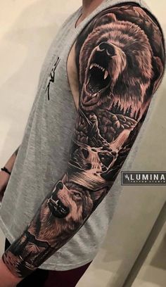 a man's arm with a bear and mountain scene tattoo on the left sleeve