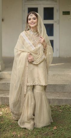 a woman in a white dress and veil posing for the camera with her hands on her hips