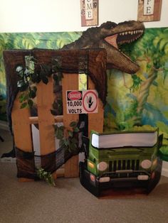 a green truck parked next to a fake dinosaur head on the wall in a room