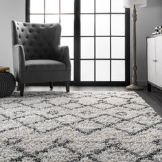 a living room with a gray chair and white rug on the floor next to a window