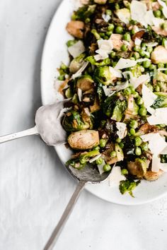 a white plate topped with lots of food next to a silver serving utensil