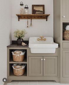 a white sink sitting next to a wooden shelf filled with baskets and flowers on top of it