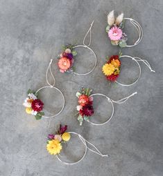 six flower headbands with white string and colorful flowers on the ends, arranged in a circle