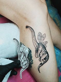 a woman laying on top of a bed next to a tattoo design that looks like dinosaurs