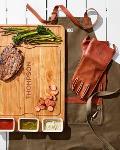 a wooden cutting board topped with meat and veggies next to a pair of gloves