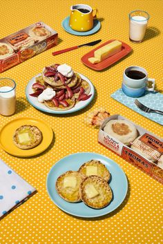 a table topped with plates of food and cups of coffee next to boxes of cookies