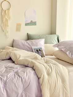 an unmade bed with pillows and blankets on it in front of a wall hanging